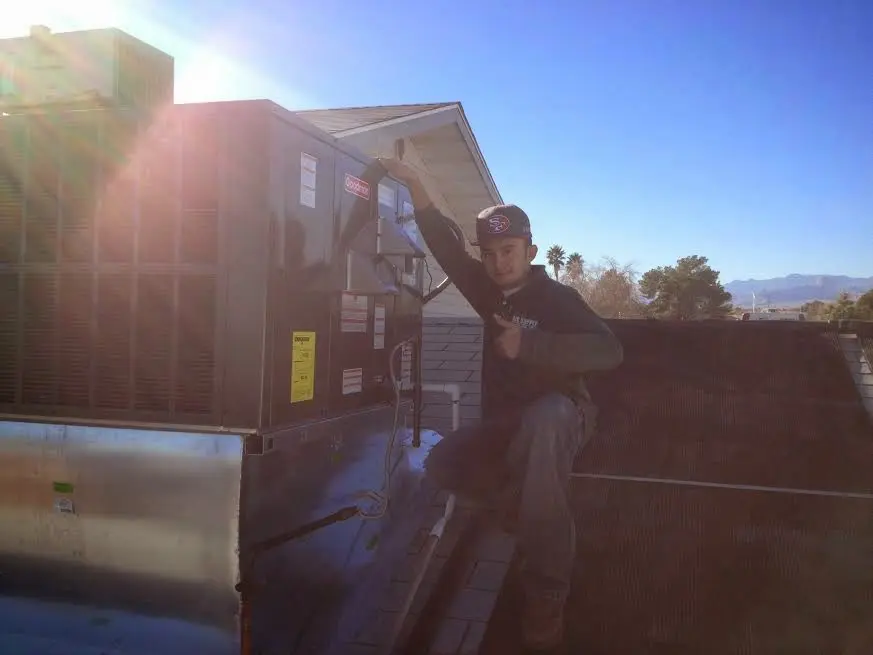 HVAC technician performing HVAC Inspection on a rooftop unit in Kula